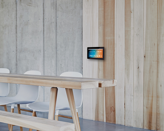 Ein Besprechungstisch aus Holz mit einem Tablet an der Wand